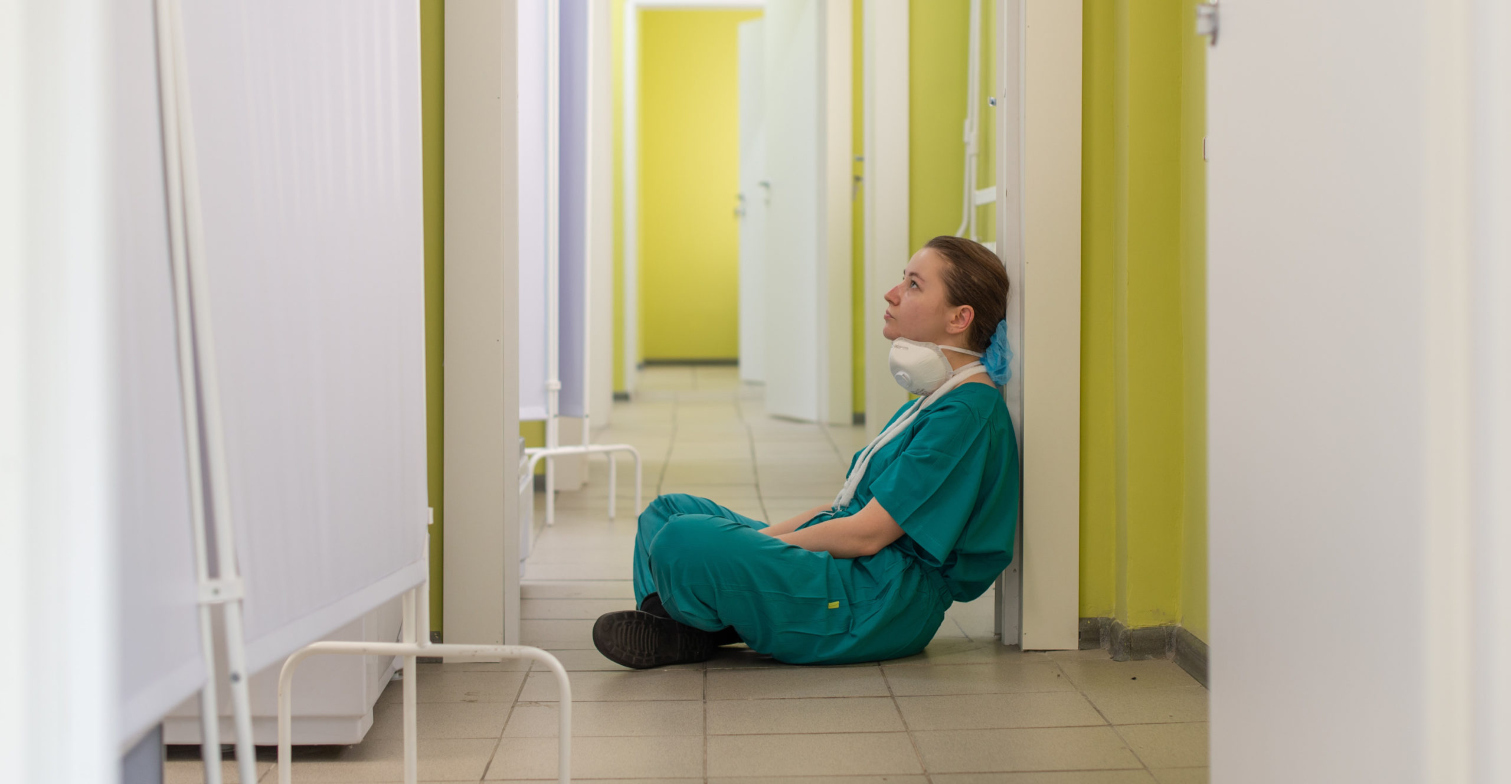 Ärztin sitzt niedergeschlagen auf Fußboden