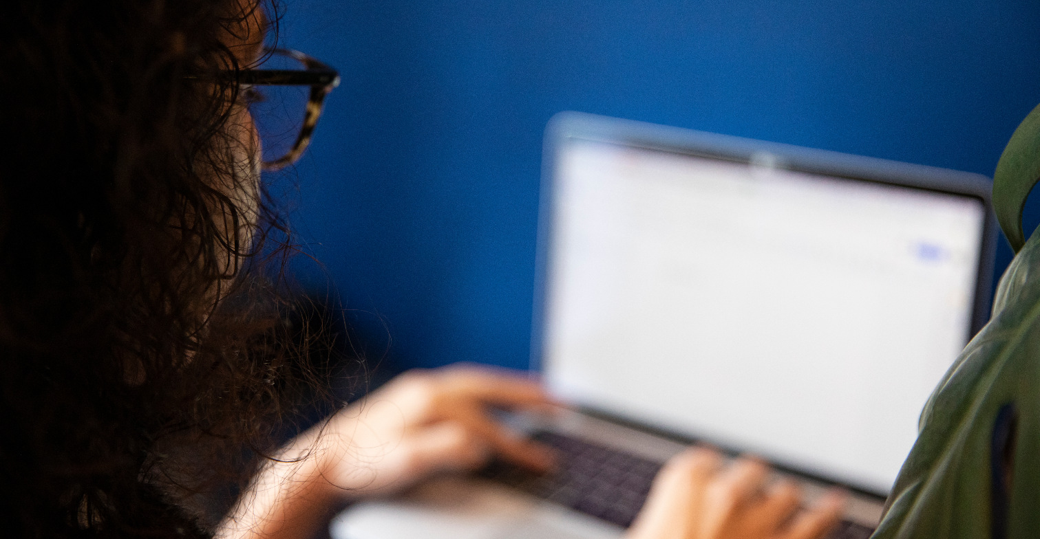 hateaid-strafteten-im-netz-doxxing-gili-dailes Eine Frau arbeitet an einem Laptop, sie ist von hinten fotografiert.