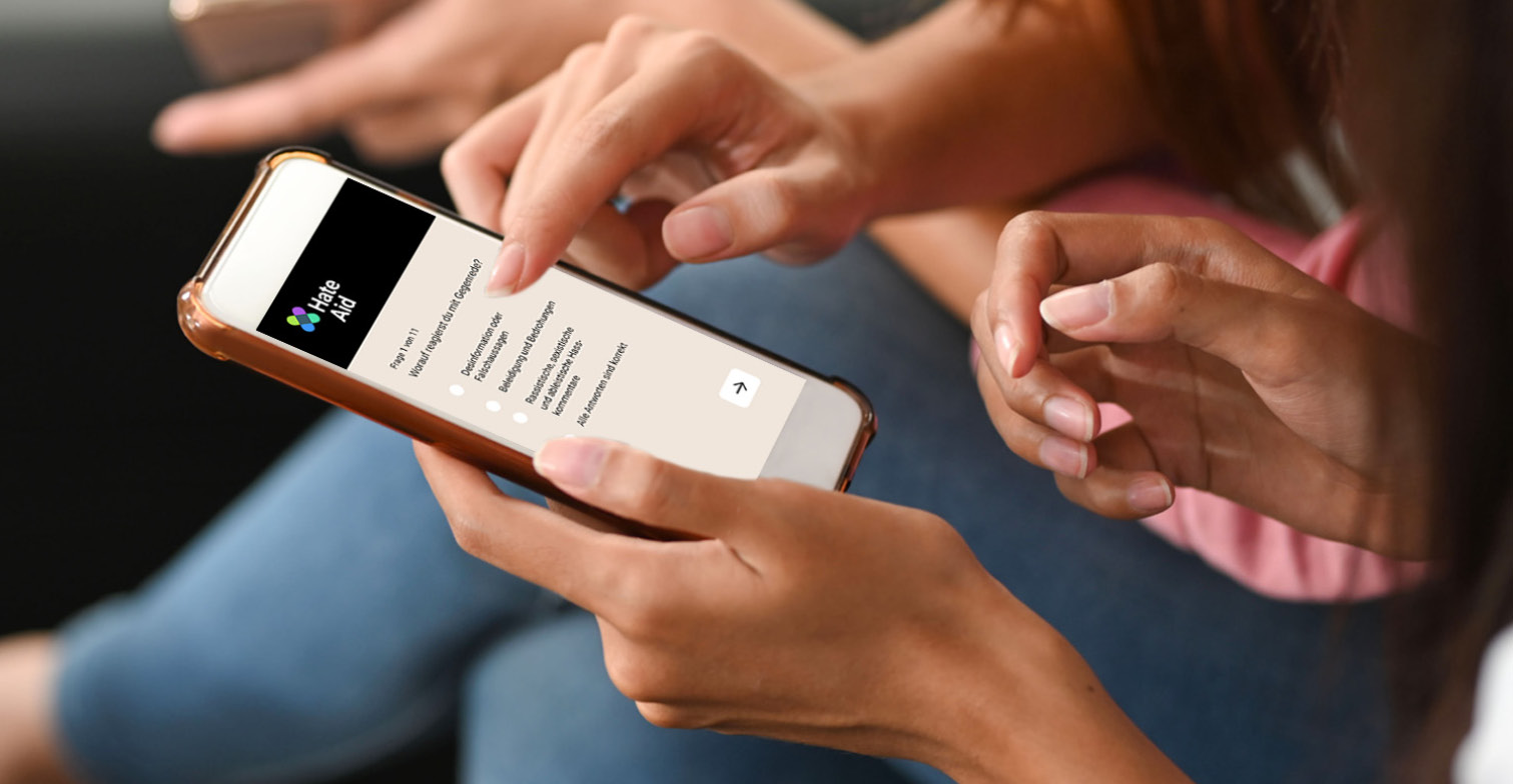 HateAid #UnserInternet Quiz zum Thema Gegenrede. Zu sehen sind zwei Personen, die ein Quiz auf einem Smartphone ausfüllen